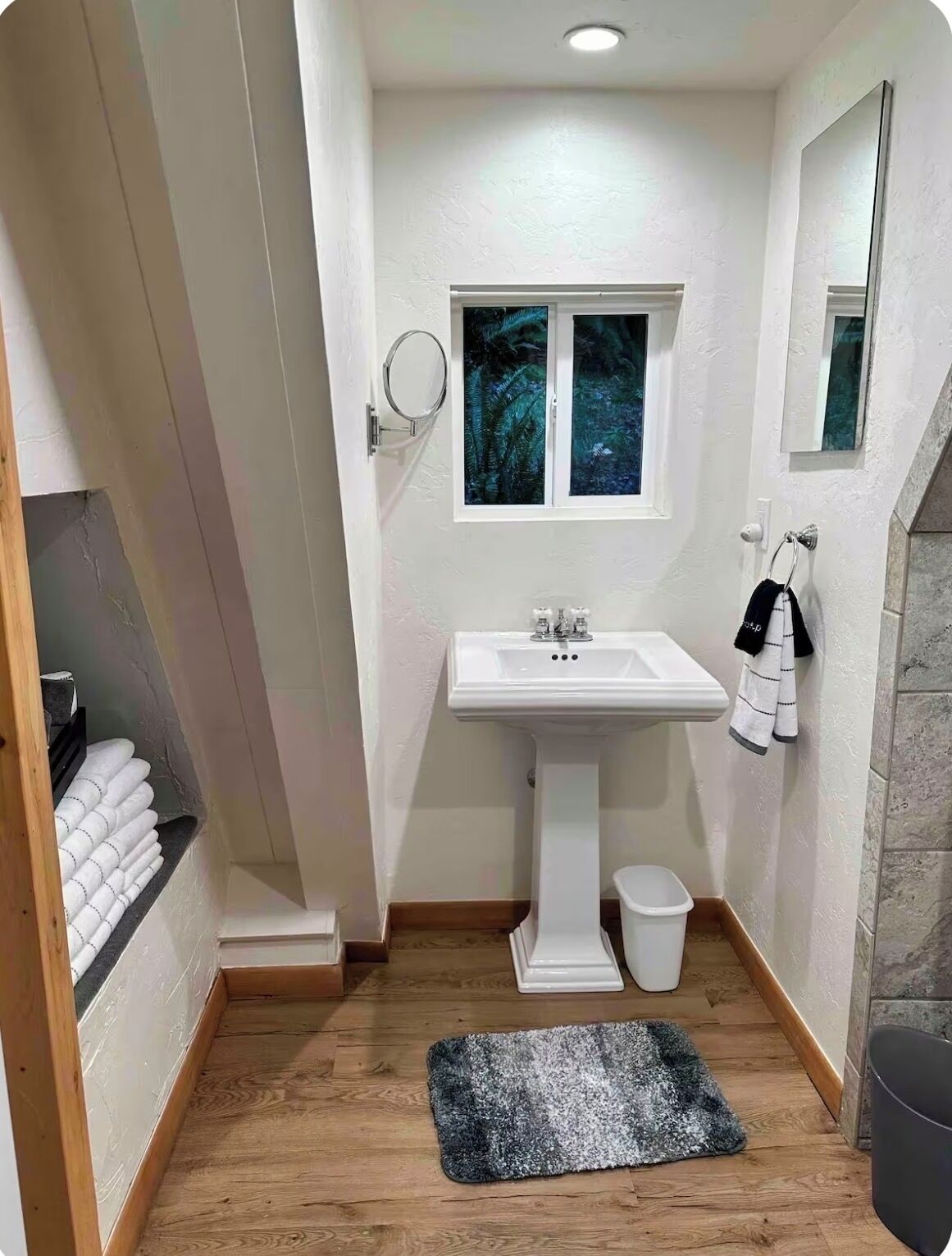 Un bagno piccolo con un lavandino bianco, una finestra, uno specchio e un porta asciugamani.