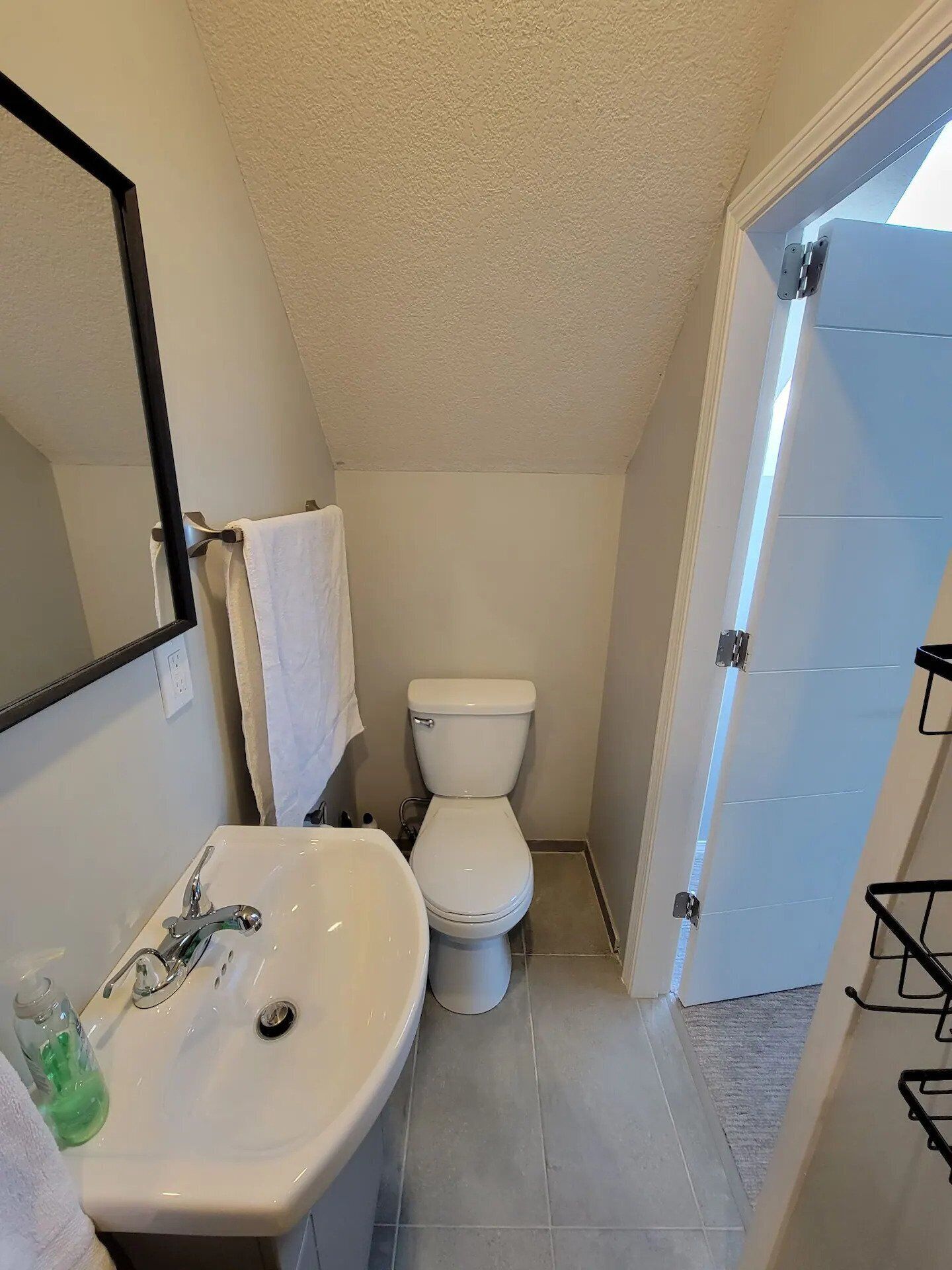 Un baño pequeño con lavamanos, inodoro y espejo blancos.