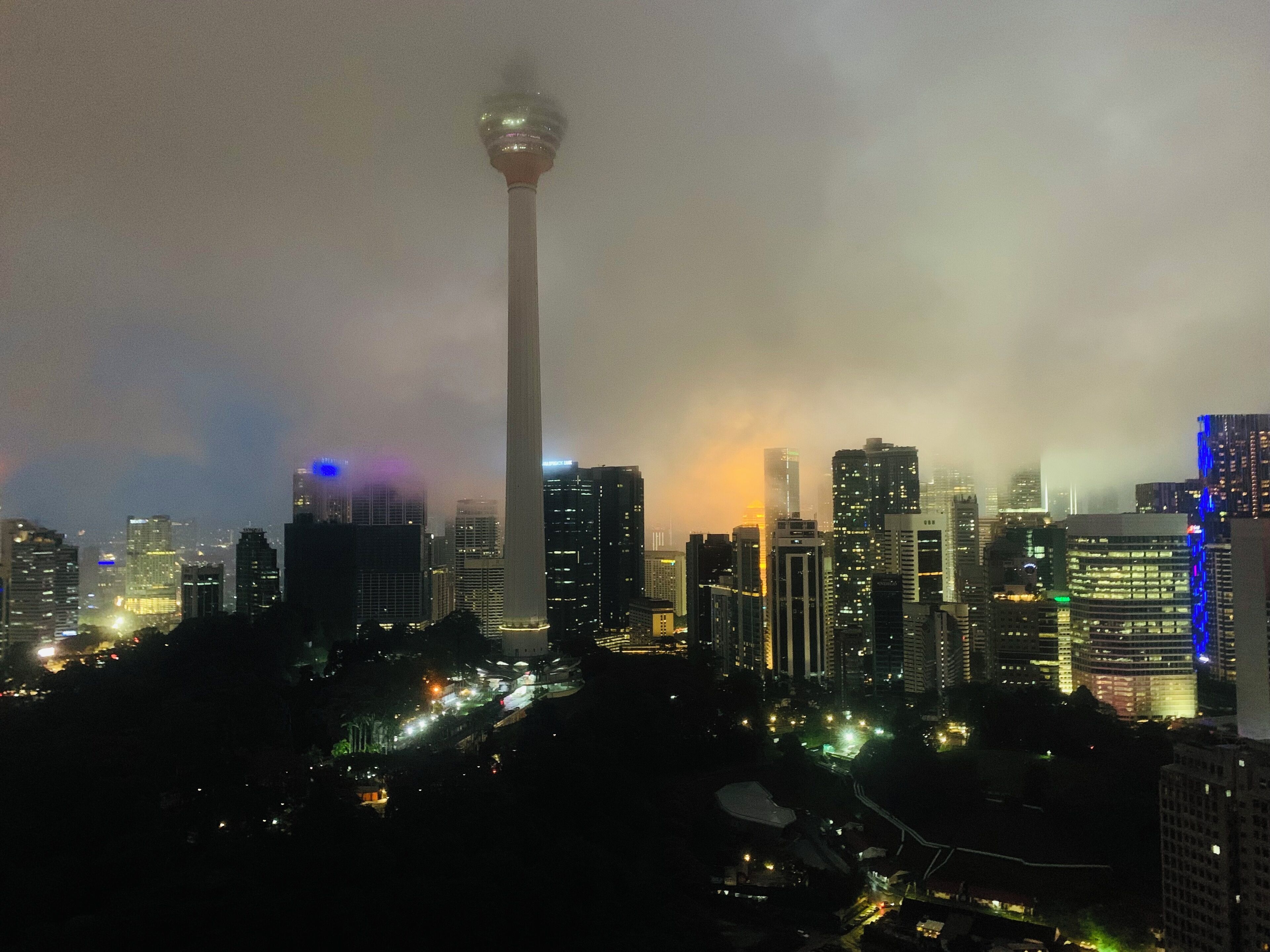 A cityscape at night with a prominent tower and illuminated buildings.