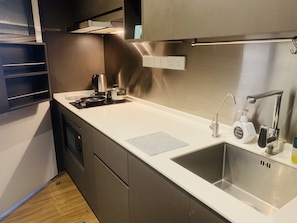 A modern kitchen with a stainless steel sink, a kettle, and a hand soap dispenser.