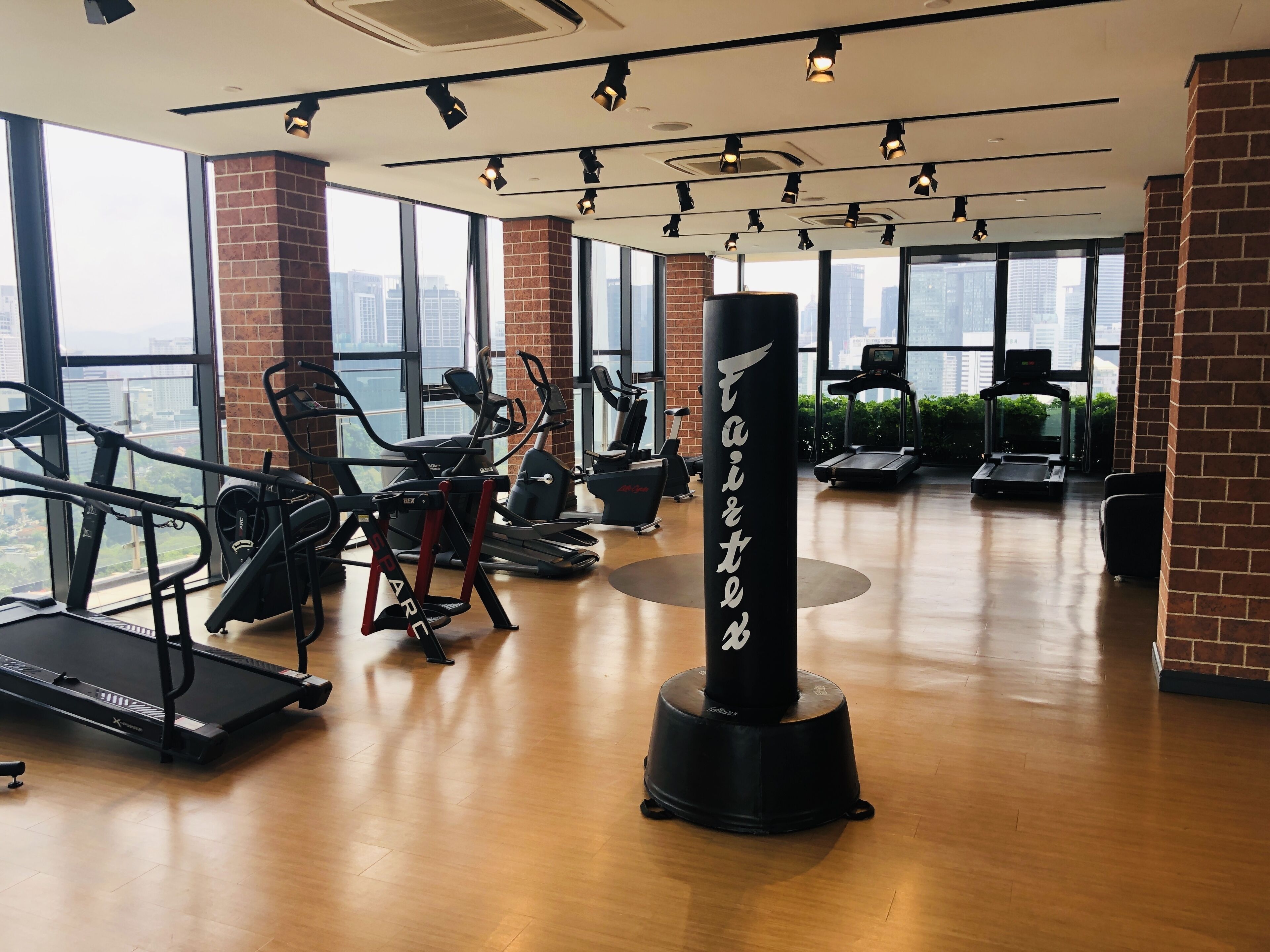 A gym with various exercise equipment, large windows, and a view of the city.