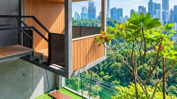 A modern outdoor balcony with a view of a city skyline, including a tower and skyscrapers.