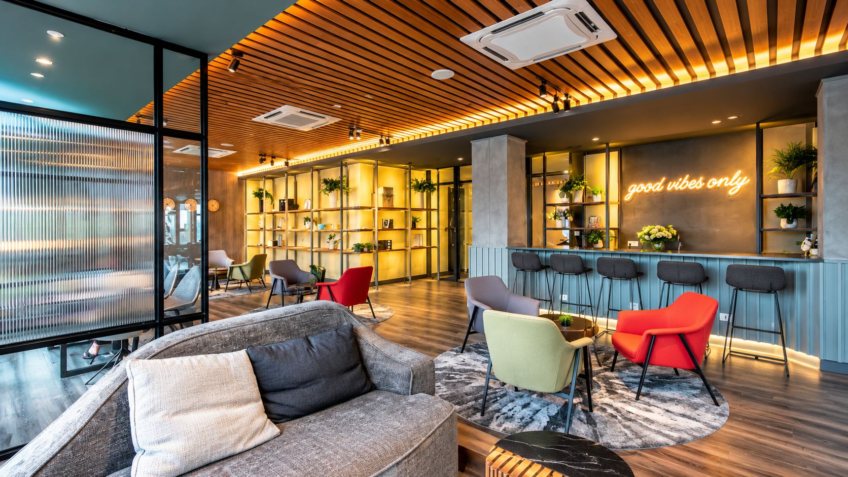 A modern lounge area with a sofa, chairs, a bar, and a bookshelf.
