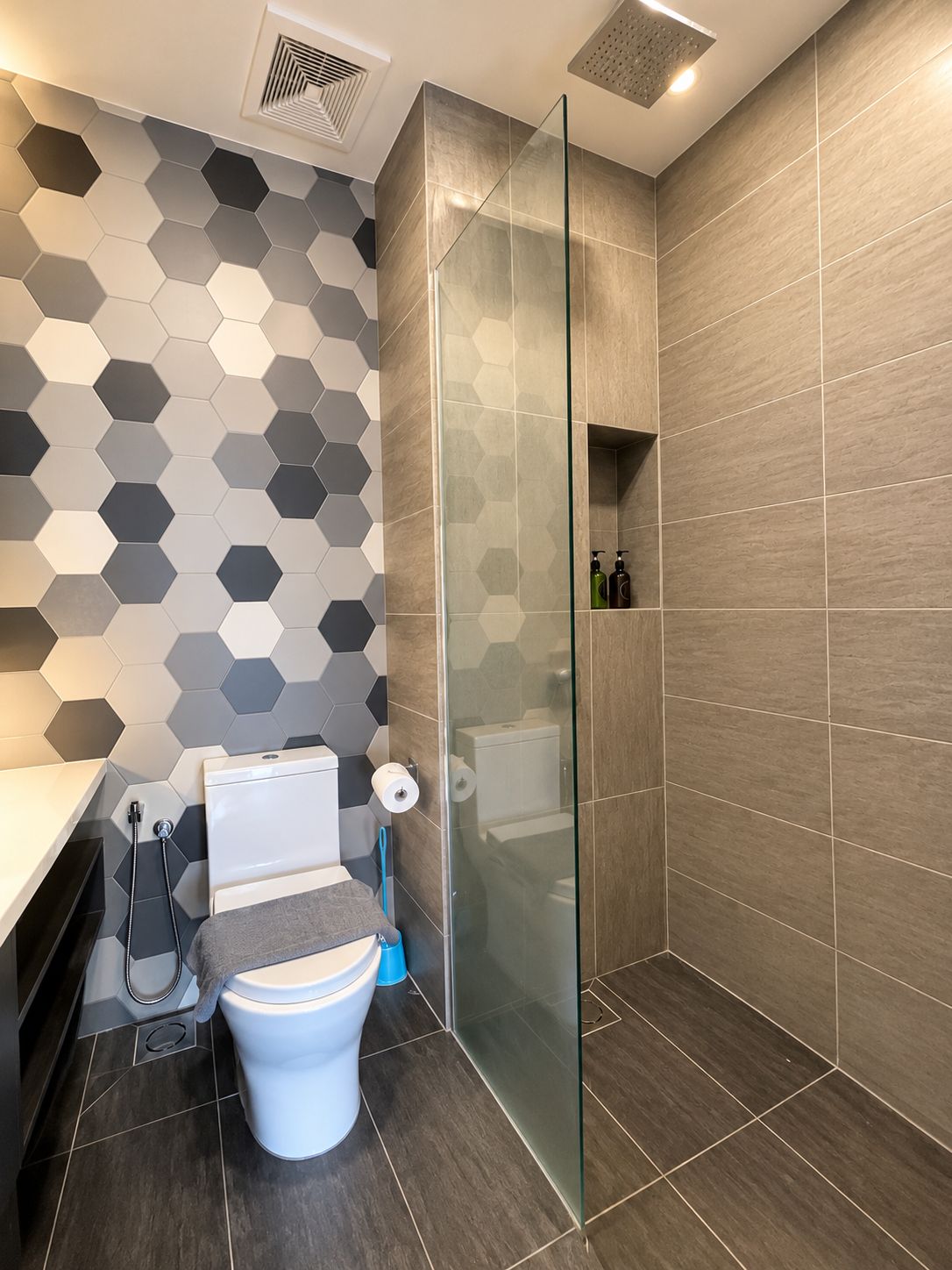 A modern bathroom with a toilet, shower, and glass-enclosed shower stall.