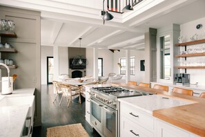 A modern kitchen with white cabinetry, a large island, and a dining area with wicker chairs.