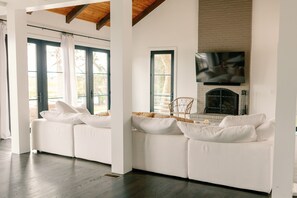 A modern living room with a white sofa set, a fireplace, and a large TV mounted on the wall.