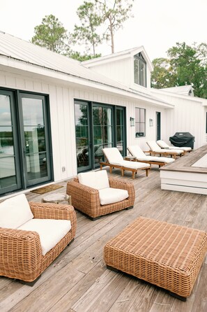 A deck with wicker furniture and a barbecue grill.