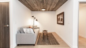 A modern living room with a grey sofa, a small coffee table, and a floor lamp. - Style Points Shelter: Downtown (Bozeman)