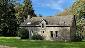 Kivitalo, jossa on kalteva katto, pieni kuisti ja sorapäällysteinen ajotie.