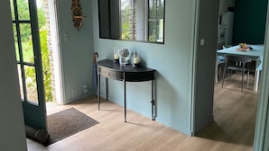 Moderni keittiö, jossa on ruokailutila, suuri peili ja näkymä puutarhaan avonaisen oven kautta.
