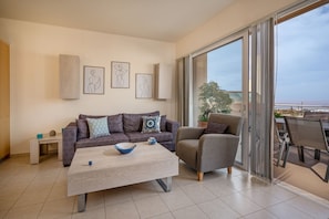 A modern living room with a sofa, armchair, coffee table, and artwork on the wall. - PP 3/60, with a common pool and sea view (Plakias)