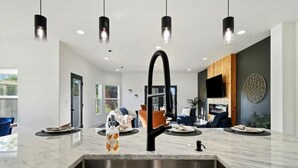 A modern kitchen with a central island, stainless steel sink, and pendant lighting. - Private Oasis On 2 Acres w/ Indoor Pool & Theater! (Eagle)