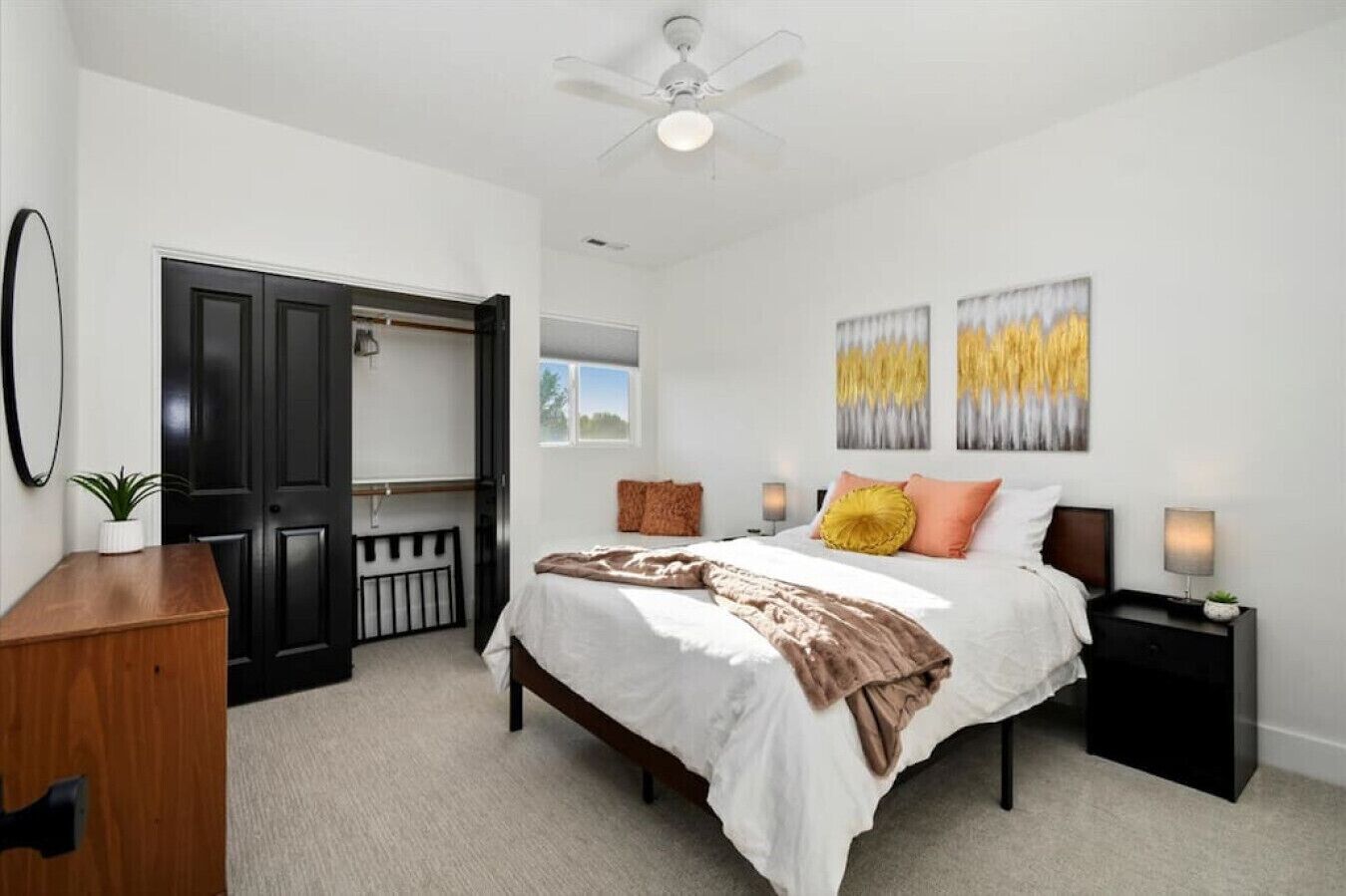 A bedroom with a bed, bedside tables, a ceiling fan, and artwork on the wall.