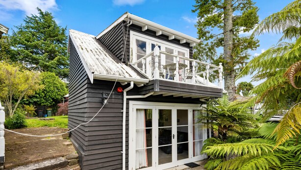 A two-story house with a balcony, a front door with glass panels, and a small porch area.