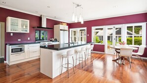 A modern kitchen with a central island, white cabinetry, and a dining area with a round table and bar stools.