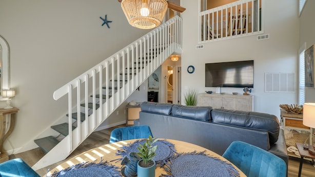 Una sala de estar moderna con una escalera, muebles azules y un televisor grande.
