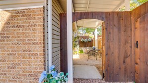 A covered patio area with a brick wall, a wooden gate, and a table with chairs. - Pet-Friendly Getaway w/ Projector in Lake Dallas! (Lake Dallas)