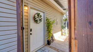 A house entrance with a white door, a welcome mat, a potted plant, and a hanging light fixture. - Pet-Friendly Getaway w/ Projector in Lake Dallas! (Lake Dallas)