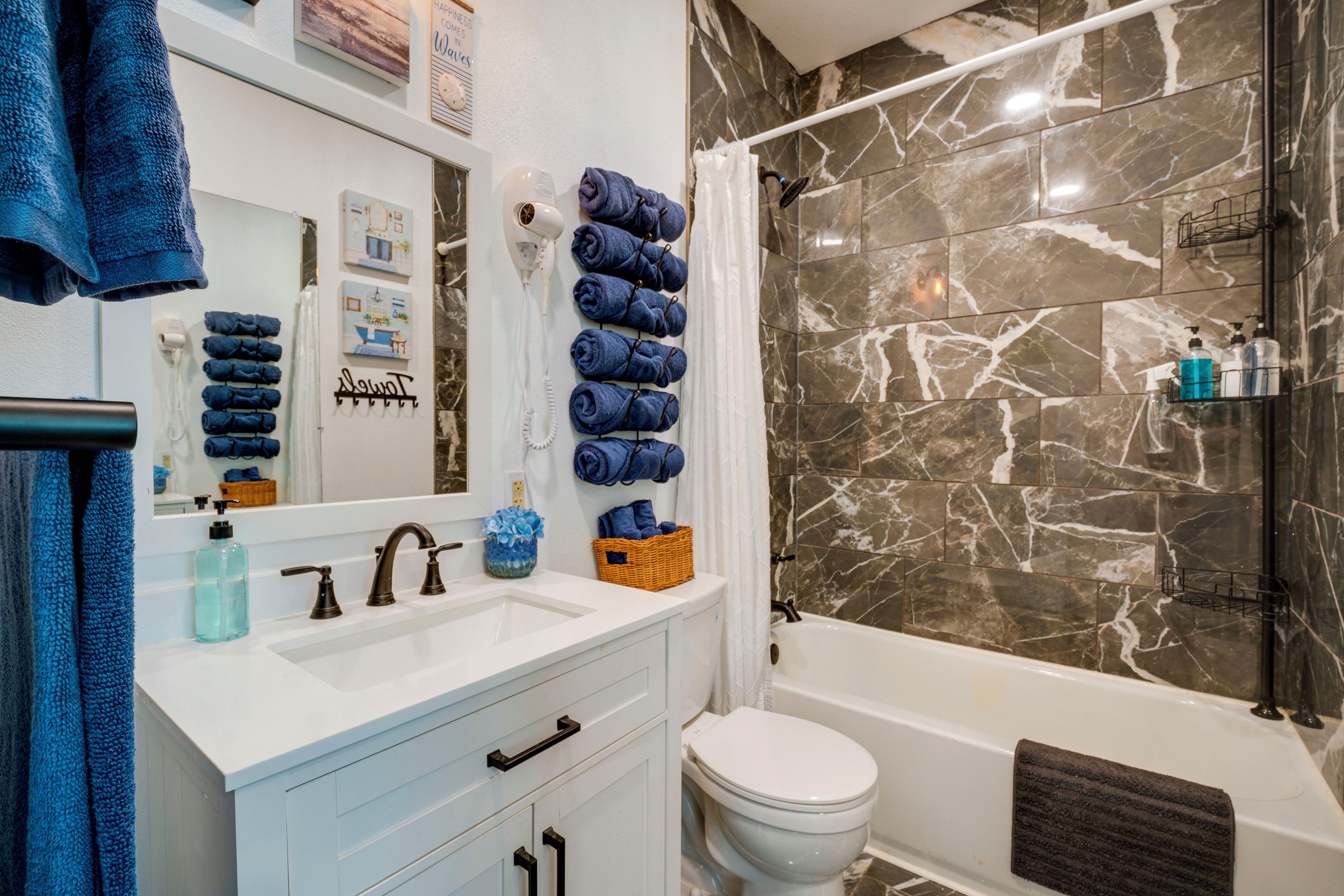 A bathroom with a white sink, two faucets, a mirror, a toilet, and a bathtub.