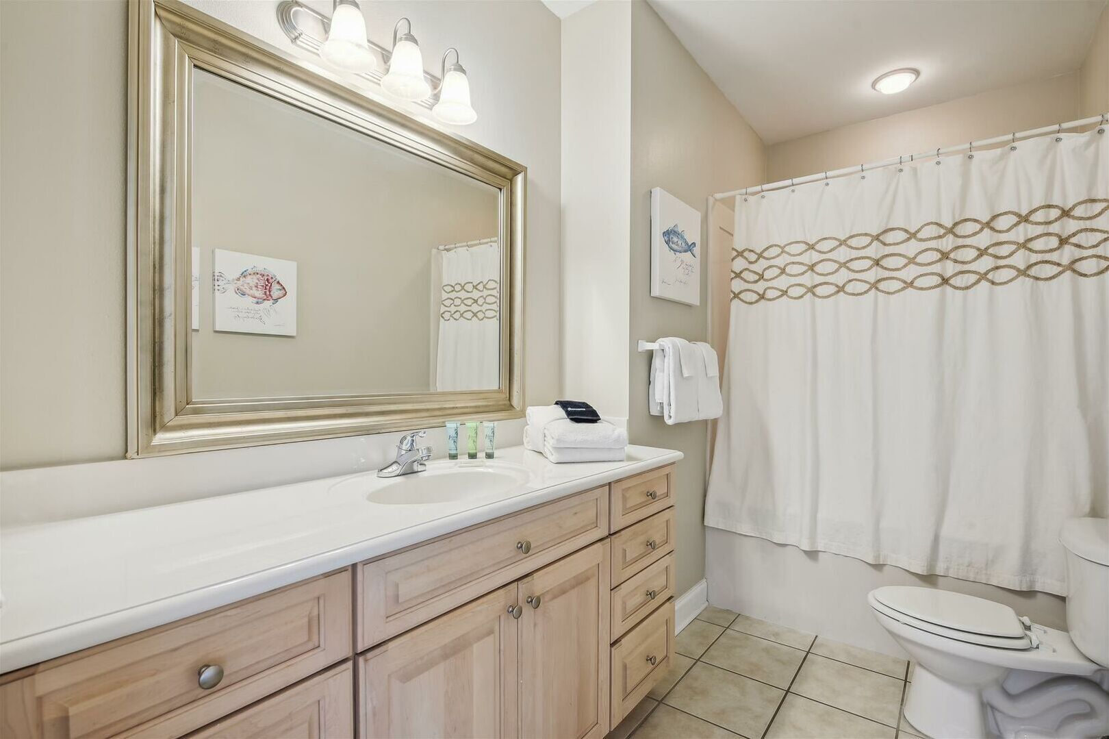 A bathroom with a large mirror, a sink, a toilet, and a shower curtain.