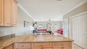 A kitchen with granite countertops, wooden cabinets, and a dining area with a red sofa.