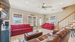 A spacious living room with a red sofa, a brown leather couch, and a ceiling fan.