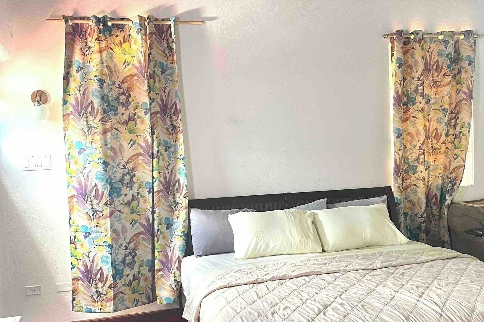 A bedroom with a bed, two nightstands, and floral curtains.