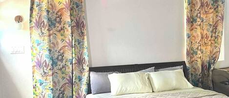 A bedroom with a bed, two nightstands, and floral curtains.