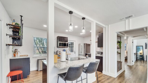 Uma cozinha moderna com uma ilha central, banquetas e iluminação pendente.