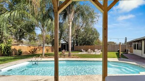 Quintal com piscina, pergolado de madeira e um pequeno galpão.