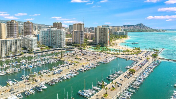 A marina with numerous boats docked, surrounded by high-rise buildings and a beach with clear turquoise waters. - Splendid 2BD w/ One FREE Parking (Honolulu)