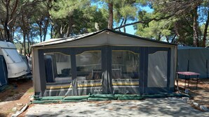 Uma área externa coberta com uma estrutura tipo tenda, uma mesa e um número '34' no chão.
