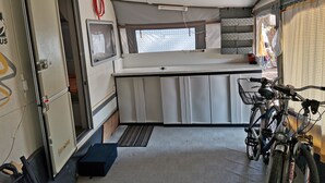 Uma cozinha compacta com pia, janela e uma bicicleta estacionada perto.