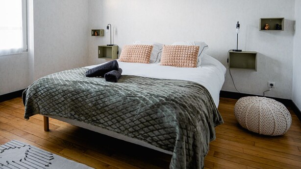 Ein modernes Schlafzimmer mit einem großen Bett, einer Hängeleuchte und einem Nachttisch mit Lampe.