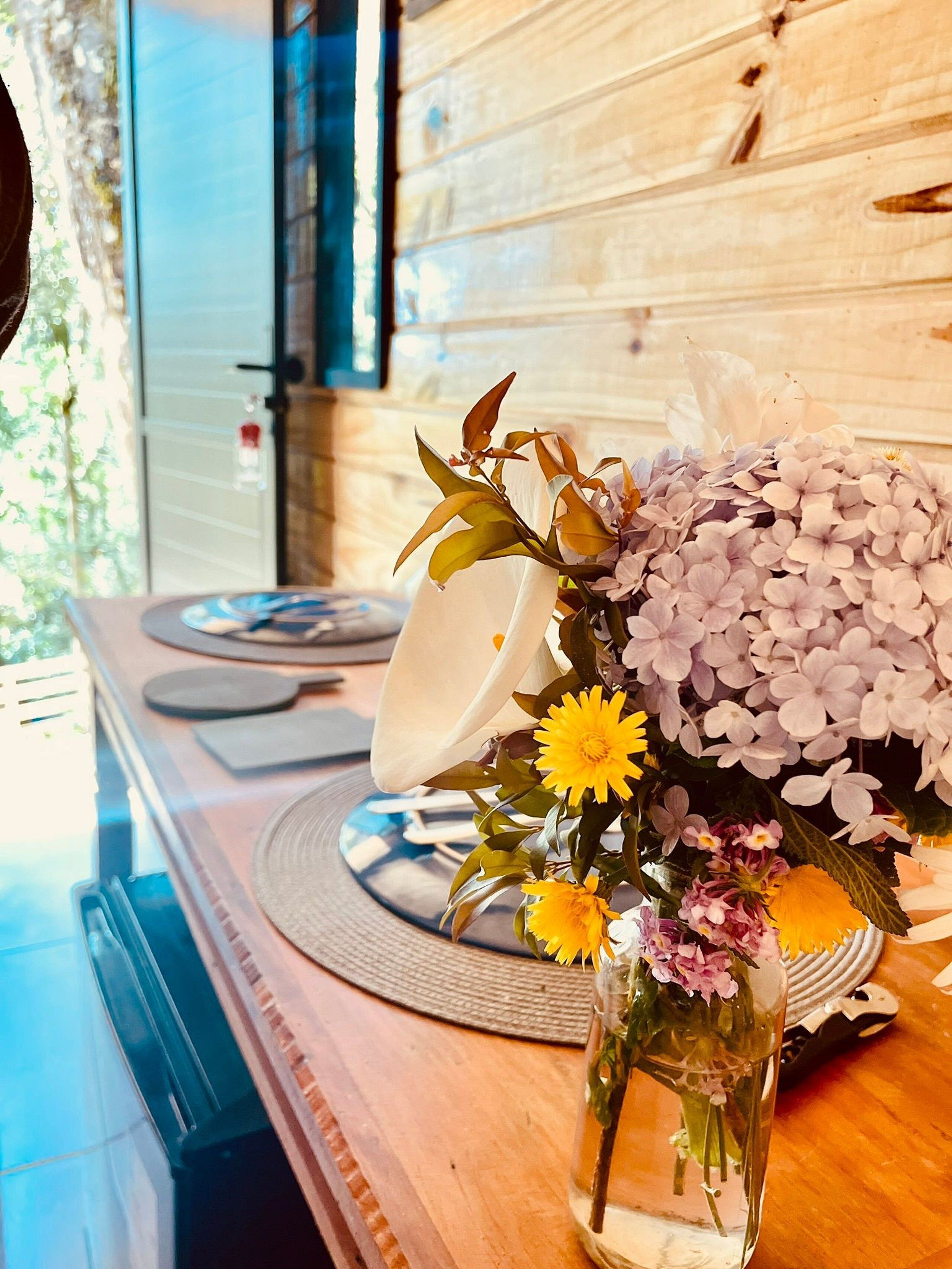 Una mesa de madera con un florero de vidrio que contiene un ramo de flores.