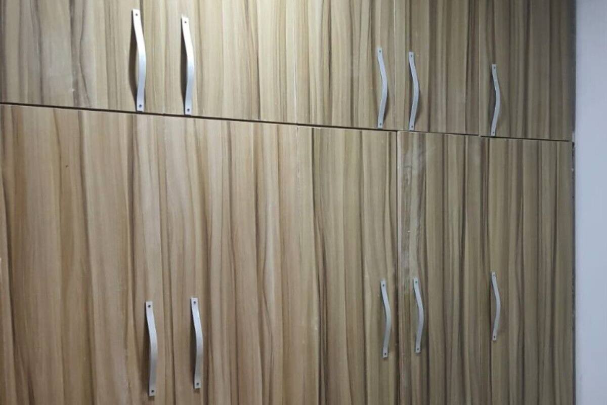 A wardrobe with vertical wood grain panels and metal handles.