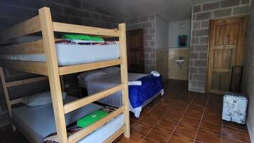 Quarto com beliche, pequeno espaço de cozinha e mala.