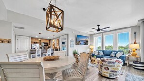 A spacious living area with a dining table, chairs, a sofa, and a ceiling fan.