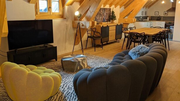 A cozy loft-style living room with a large TV, a sofa, and a dining area with a wooden table and chairs. - 2nd floor, tv, ski locker, 78m², Serre Chevalier (Le Monêtier-les-Bains)