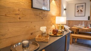 Eine Holzwand mit einem gerahmten Bild, ein Tisch mit einer Lampe und eine Bank.