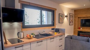 Eine moderne Küche mit Einbauofen, Spüle und einem Fenster darüber. Ein graues Sofa und ein Flachbildfernseher sind an der Wand befestigt.