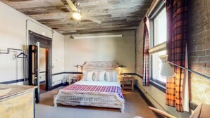 A bedroom with a bed, a ceiling fan, a window with curtains, and a door. - Benson Lodge Room -2 (Silverton)