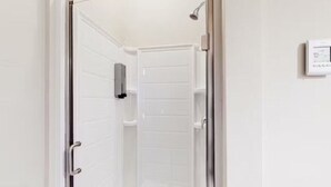 A modern bathroom with a glass shower enclosure, a white toilet, and a wall-mounted control panel. - Benson Lodge Room - 6 (Silverton)
