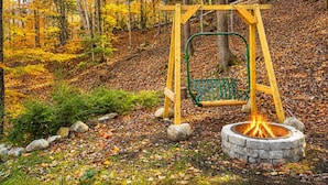 A swing set with a fire pit in a wooded area. - Beautiful Chalet 2 minutes from the Saco River 🚣🔥🌲🗻 (Bartlett)