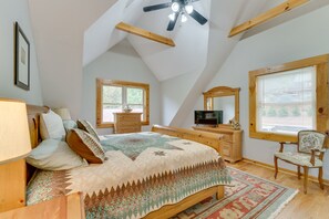A bedroom with a sloped ceiling, a bed, a dresser, a chair, a television, and a window with blinds. - Serene Cabin w/ Deck & Fire Pit in Blue Ridge Mtns (Bostic)