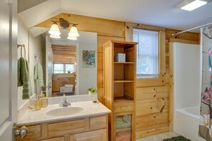 A bathroom with a wooden vanity, a sink, a mirror, and a shower area. - Serene Cabin w/ Deck & Fire Pit in Blue Ridge Mtns (Bostic)