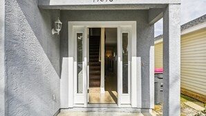 A house entrance with a number '11818' above the door, a set of stairs leading inside, and a light fixture on the wall. - Baberville By Book That Condo (Panama City Beach)