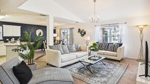 A modern living room with a sofa, coffee table, and a dining area in the background. - Baberville By Book That Condo (Panama City Beach)