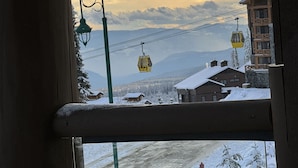 A view of a snowy mountain landscape with a ski lift and buildings in the background.