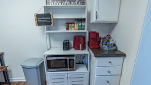 Cocina compacta con microondas, tostadora, cafetera y armarios de almacenamiento.